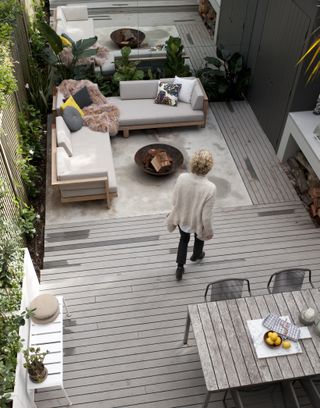 A backyard with grey decking and L-shaped outdoor sofa furniture decor