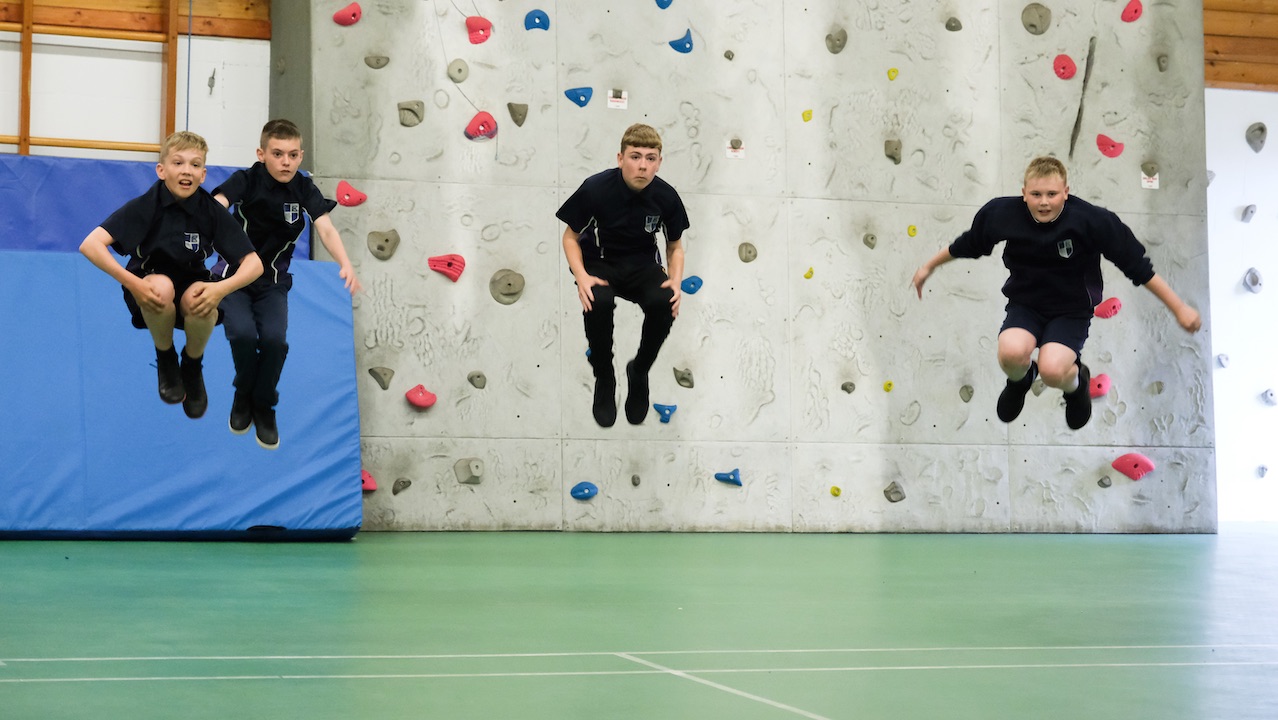 Boys jumping in front of a climbing wall