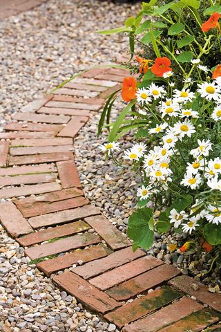 brick pathway curving around the edge of a flowerbed