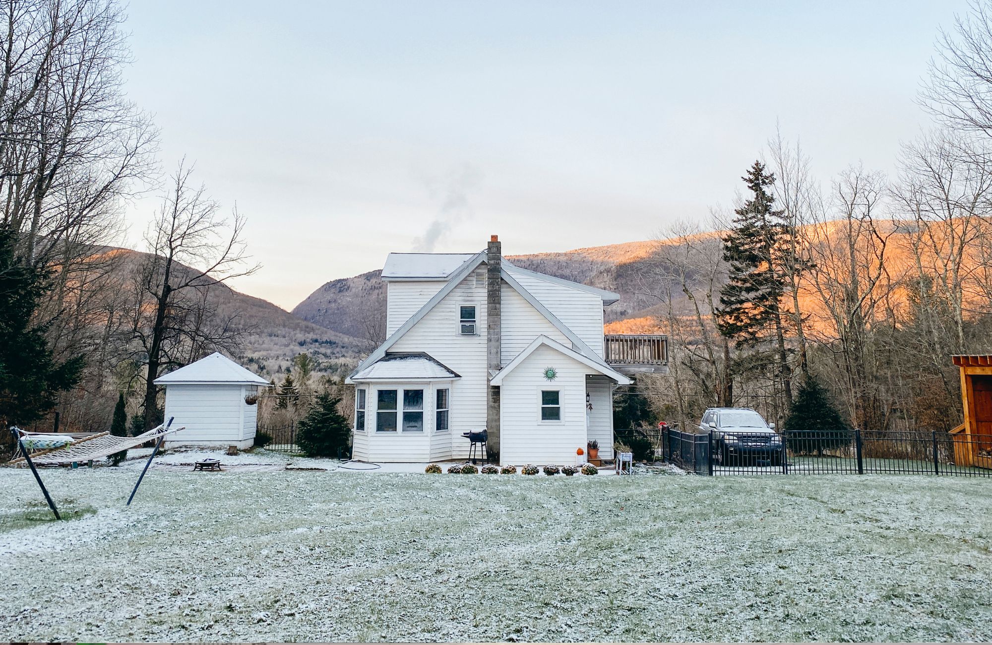Backyard view of frosted lawn and home with mountain views in winter