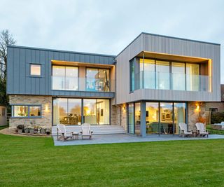 Contemporary timber and brick clad self build with large projecting balcony on the first floor and outdoor seating areas on the ground floor.