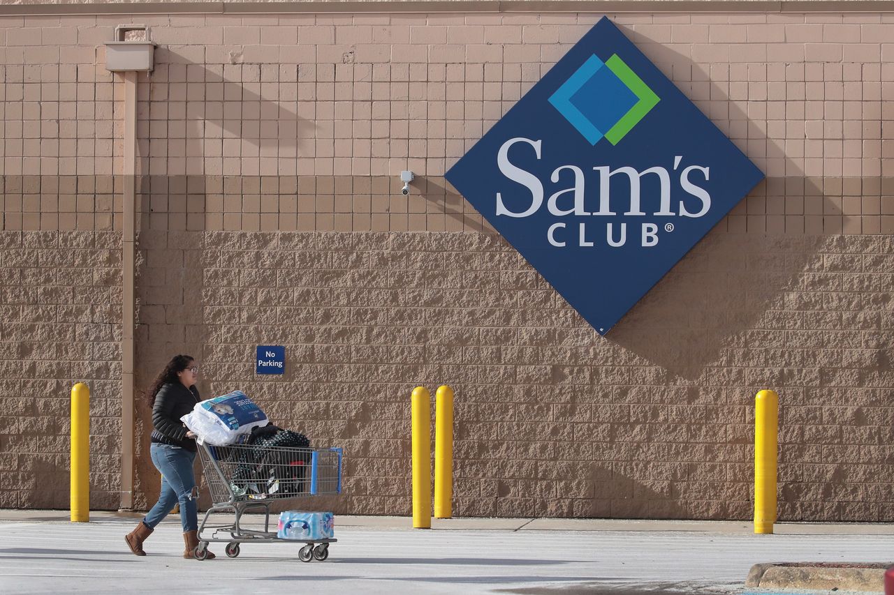 A photo of a person outside Sam&amp;#039;s Club with a shopping cart full of goods