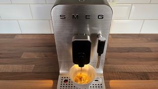 The Smeg Bean to Cup BCC02 coffee machine being used to brew espresso
