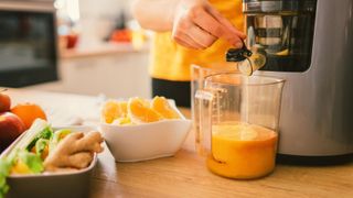 Woman juicing oranges in a cold press juicer.