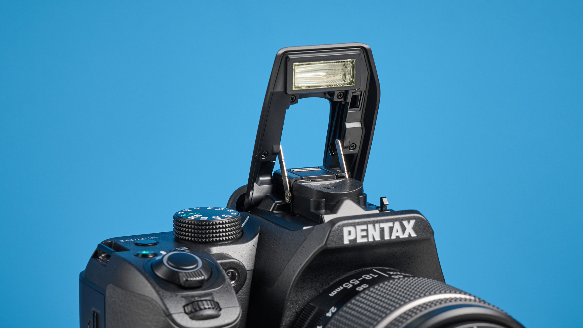 Pentax KF DSLR camera photographed on a blue background