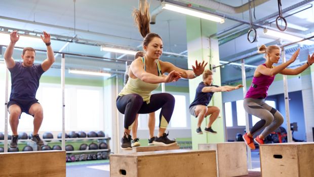 People perform box jumps in gym