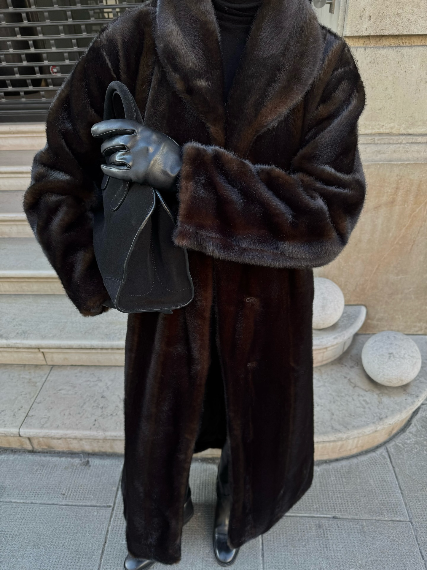 Street style photo of woman wearing a long fur coat.