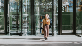 Woman walking outside office with coffee