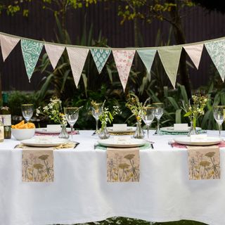 outdoor garden setting with bunting, wildflower theme, napkins, bud vases, place settings