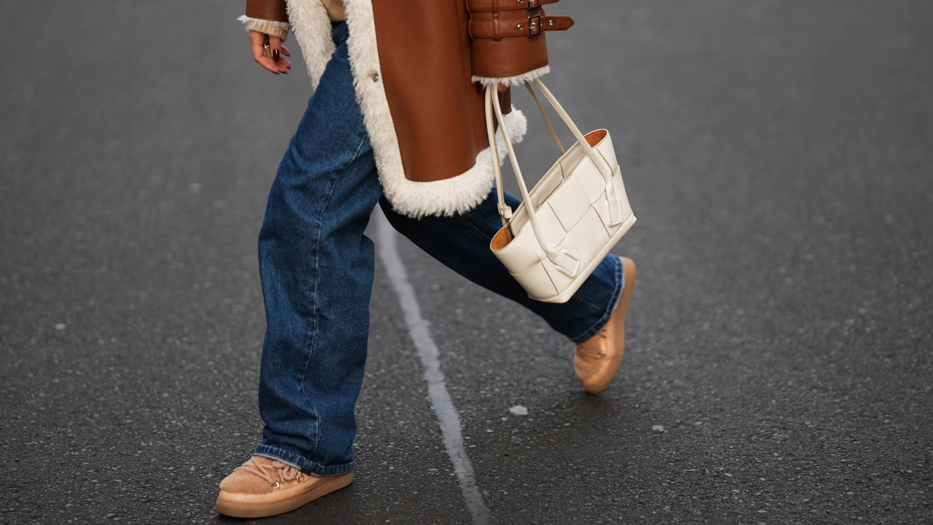 BERLIN, GERMANY - NOVEMBER 25: Laura Noltemeyer is seen wearing a shearling lining coat in a rich cognac tone with an oversized straight silhouette, wide lapels and buckle-strap cuff detailing on the sleeves from Max&amp;Co; layered underneath is a soft beige wool-blend knit sweater with a ribbed crew neckline and ribbed trims from Sézane; dark-blue straight-leg denim trousers with a classic fit from By Aylin Koenig; beige suede winter boots with a rounded toe, exposed stitching and shearling lining from Inuikii; a white structured leather top-handle bag in an intrecciato weave and trapeze silhouette called \201cIntrecciato Tote\201d from Bottega Veneta on November 25, 2025 in Berlin, Germany. (Photo by Moritz Scholz/Getty Images)