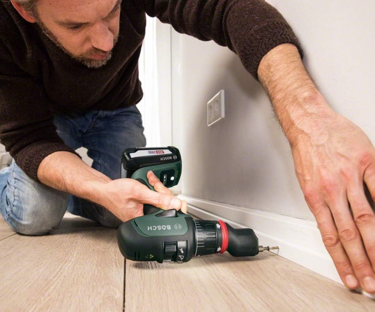 Bosch AdvancedImpact 18V cordless drill being used by man to secure skirting