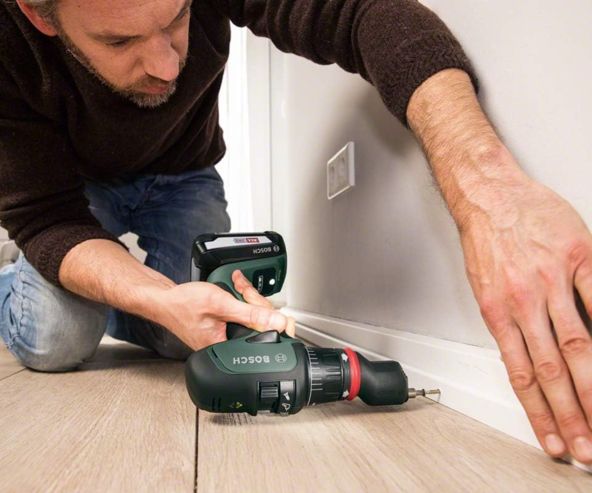 Bosch AdvancedImpact 18V cordless drill being used by man to secure skirting