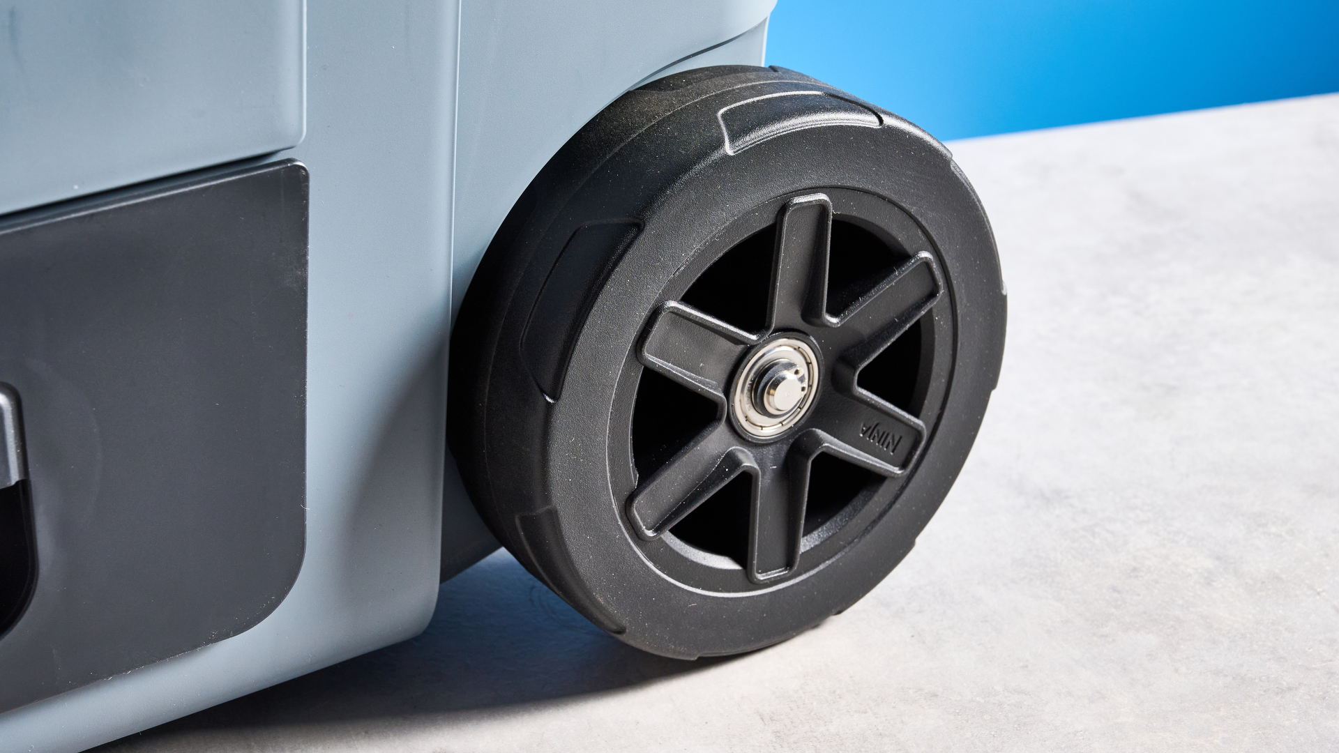 The wheels of the Ninja FrostVault 45QT Wheeled Cooler photographed in front of a blue background.