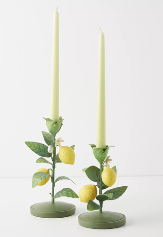two candlesticks with a lemon design holding light green tapered candles