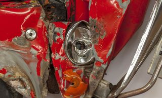Close-up view of a crushed red car's headlight and indicator