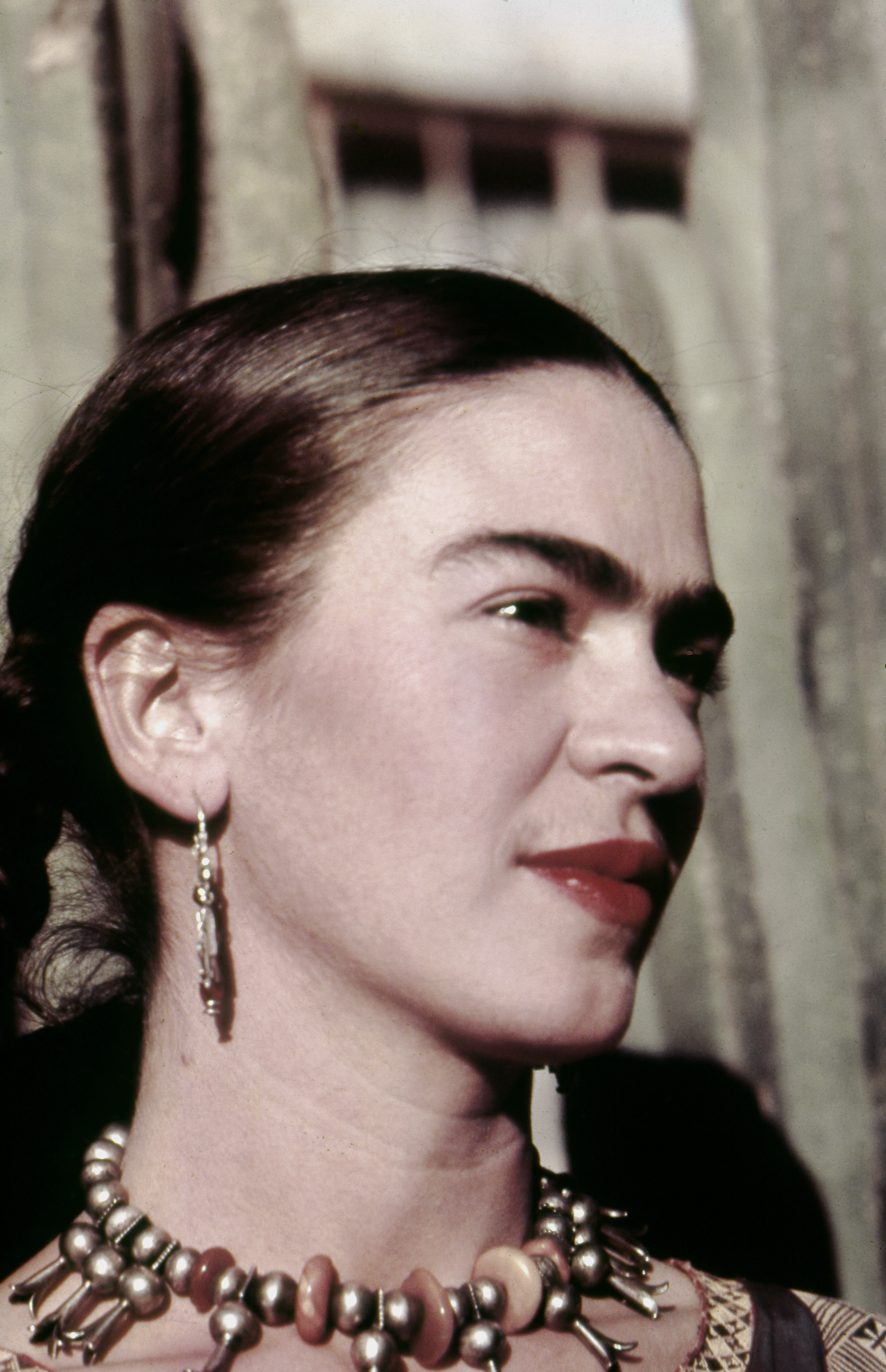 Frida Kahlo wearing red lipstick and a beaded necklace