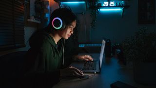The best laptops for gaming as presented by a photo of a woman playing on a laptop in the dark