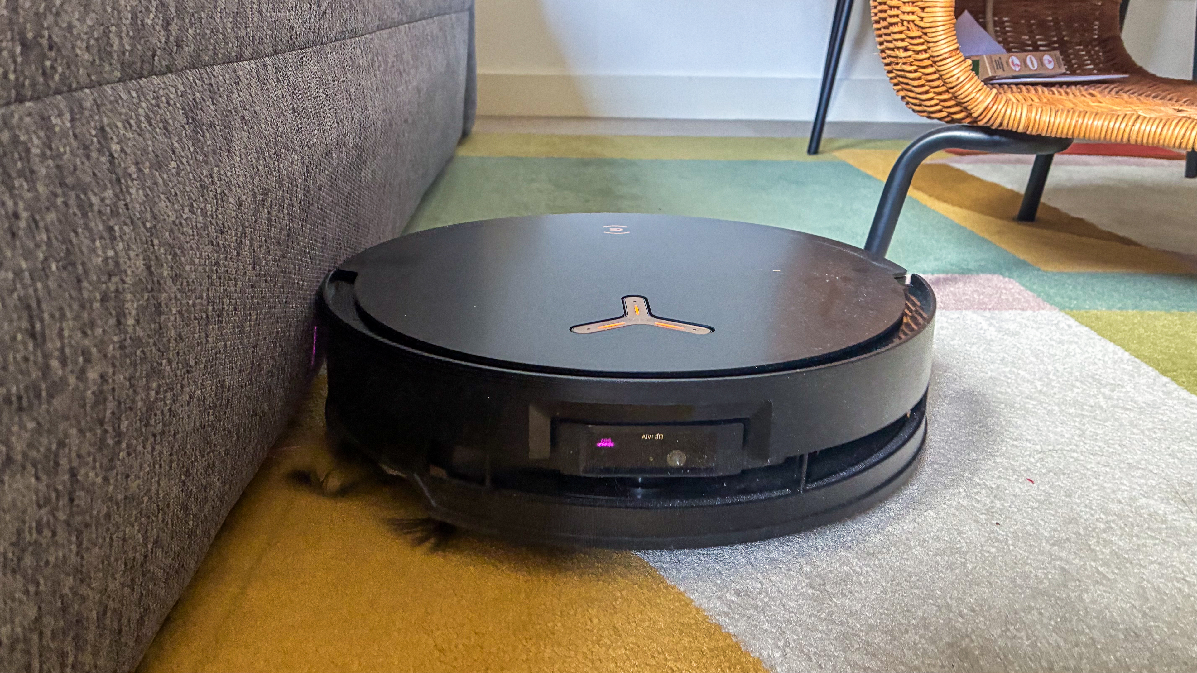 The Ecovacs Deebot X8 Pro Omni vacuuming on a carpet while traveling right along the edge of a couch