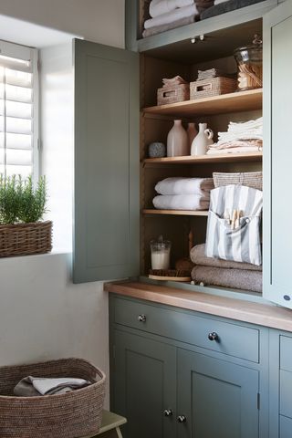 An example of utility room shelving ideas showing shelves sat neatly inside an olive-green cupboard