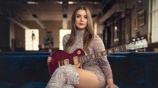Ally Venable sitting on a sofa holding a guitar