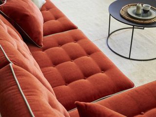 An burnt orange coloured sofa with contrasting piping