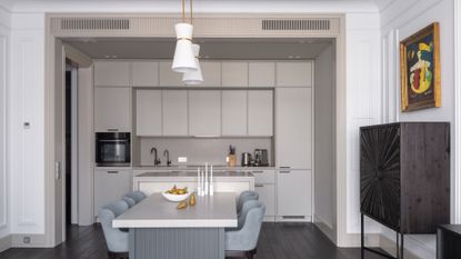 A kitchen with a dining table and hanging lamps