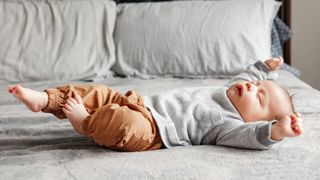 Active sleep in newborns illustrated by baby sleeping with arms stretched out