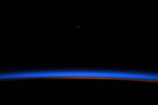 A tiny sliver of the crescent moons gleams above Earth's blue horizon just before sunrise in this stunning view from the International Space Station. NASA astronaut Christina Koch shared this image from space on Monday (Oct. 28), one day after the moon reached its new phase.