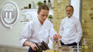 Marcus Wareing watches on as heat one contestant Anastasia prepares a dish in MasterChef: The Professionals
