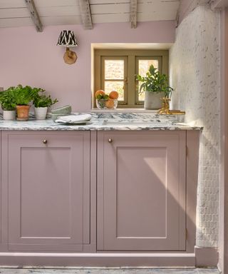 pink cottage kitchen with marble worktops and side wall tap