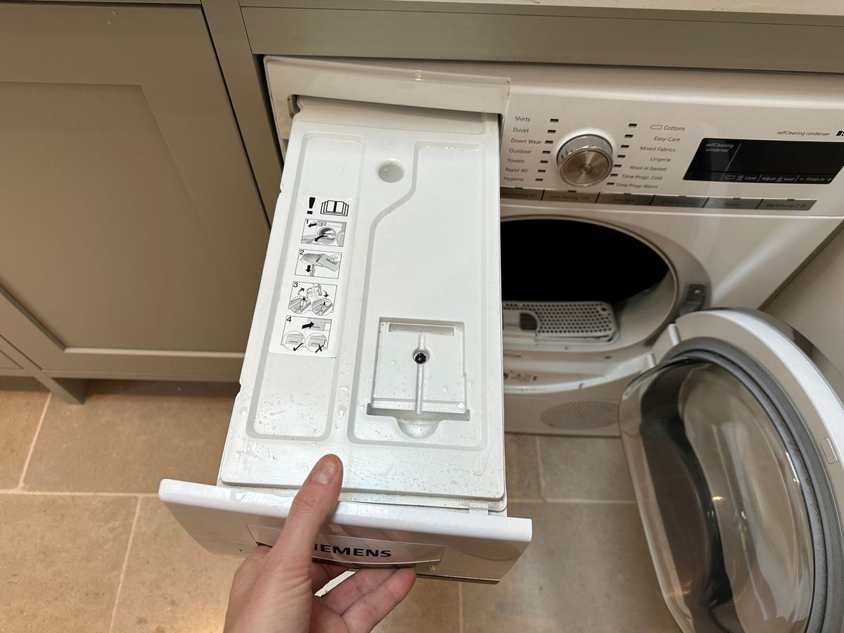 Removing the water tank from the tumble dryer to empty the water