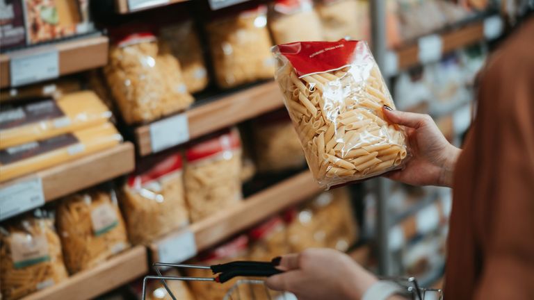 Image shows person choosing pasta in grocery store