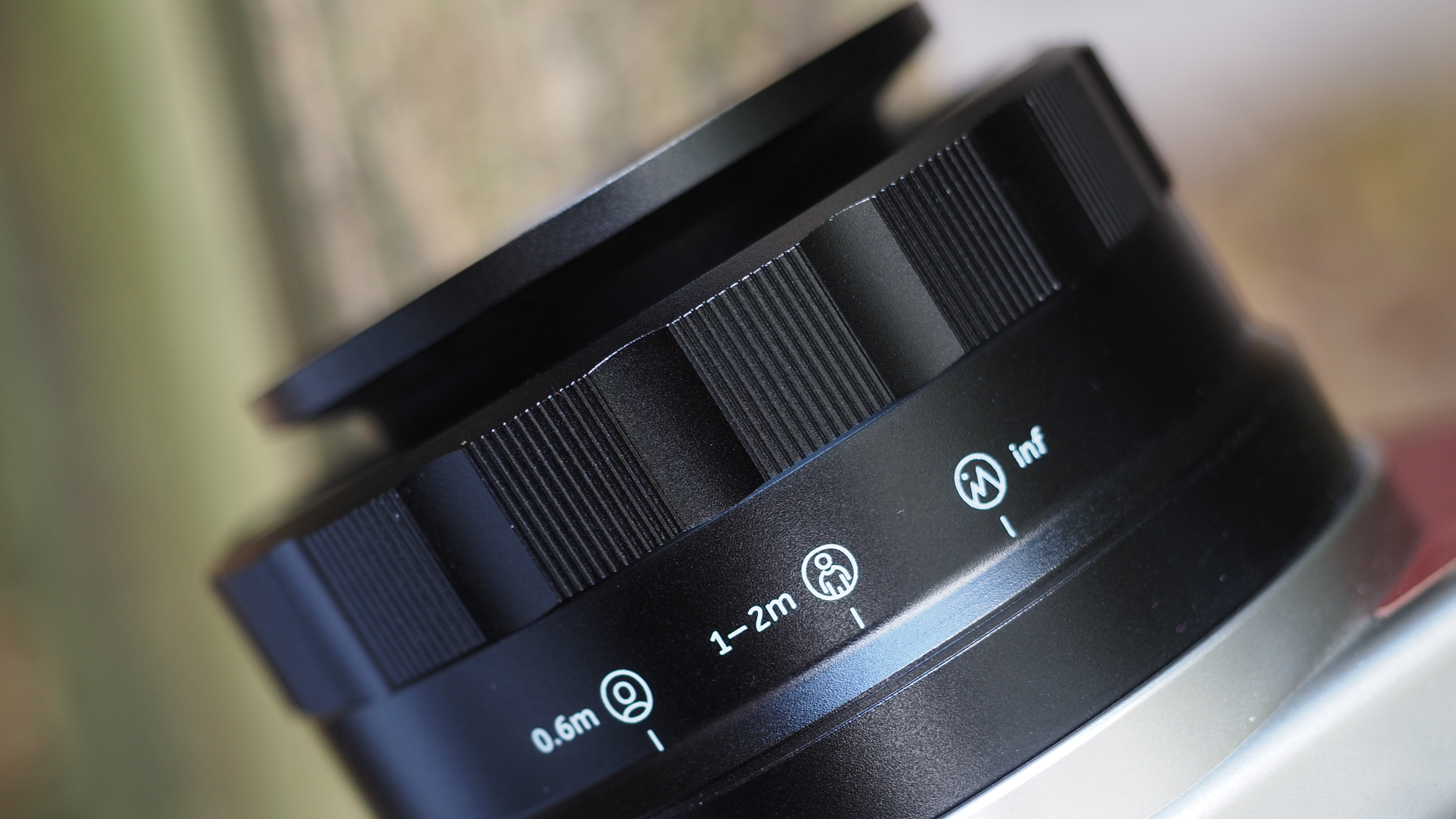 Close-up of the scale marks on the Lomo'Instant Wide Glass camera lens, placed on a wooden surface