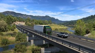 A truck crosses a bridge in a green hilly environment