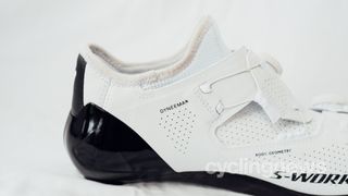 The heel of a white and black road cycling shoe