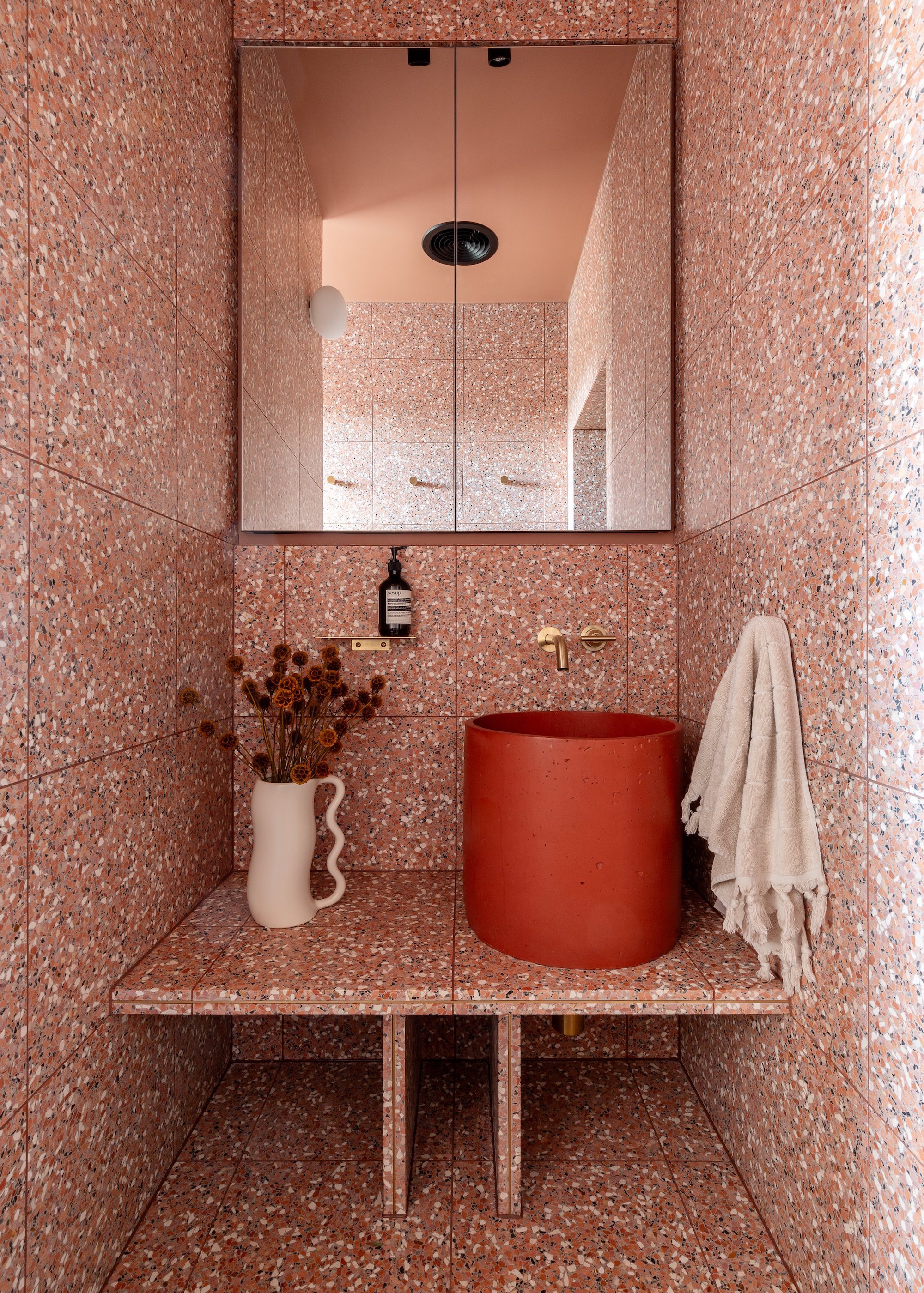 small ensuite bathroom with red vessel basin and terrazzo wrapped walls