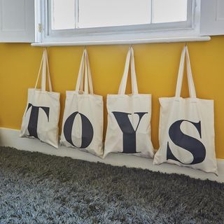 kids room with yellow wall and hanging toy storage bags