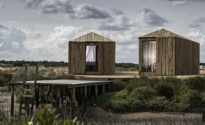 Wooden cabanas next to a wooden jetty overlooking the natural reserve of the Sado estuary
