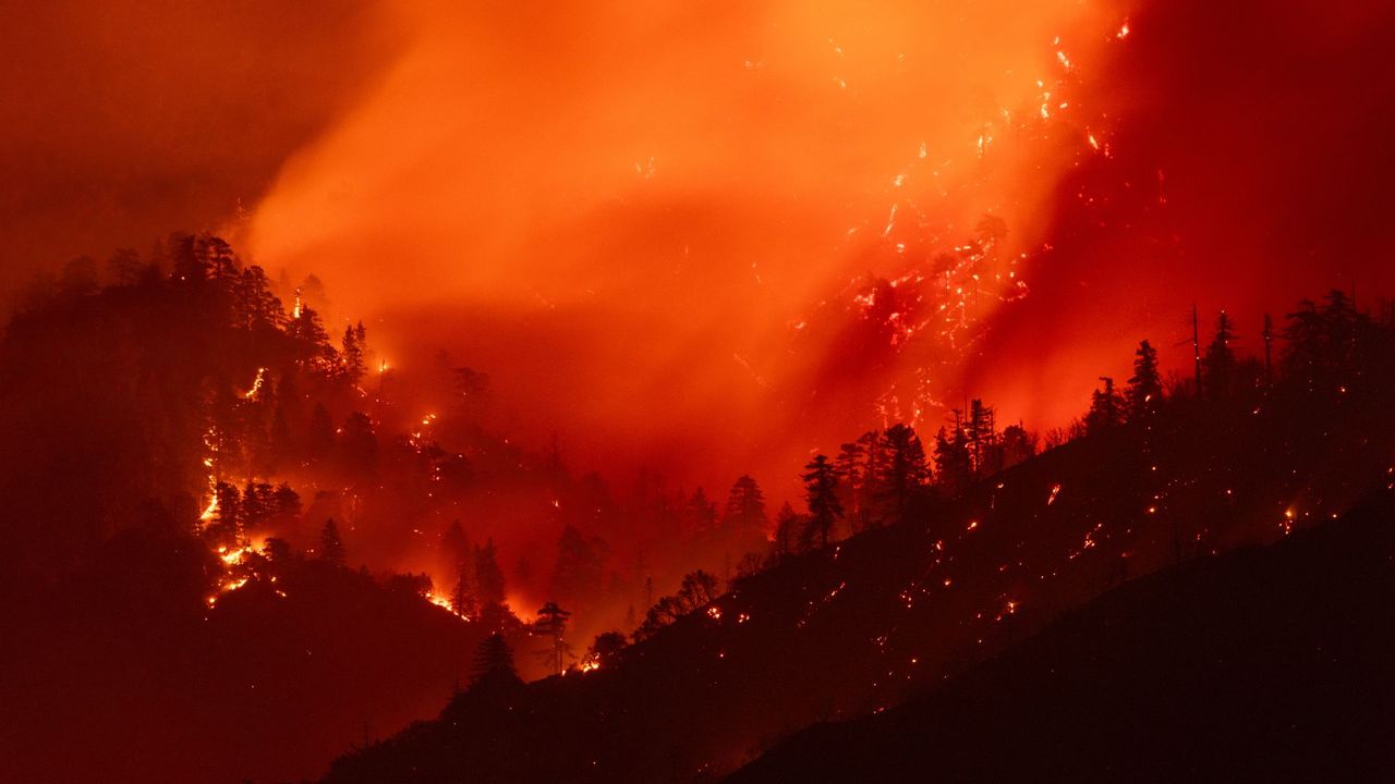 A landscape photo of forests in a mountainous area burning