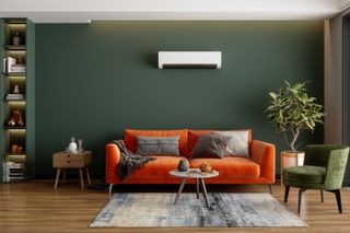 Air conditioning unit on a wall above a sofa in a green living room