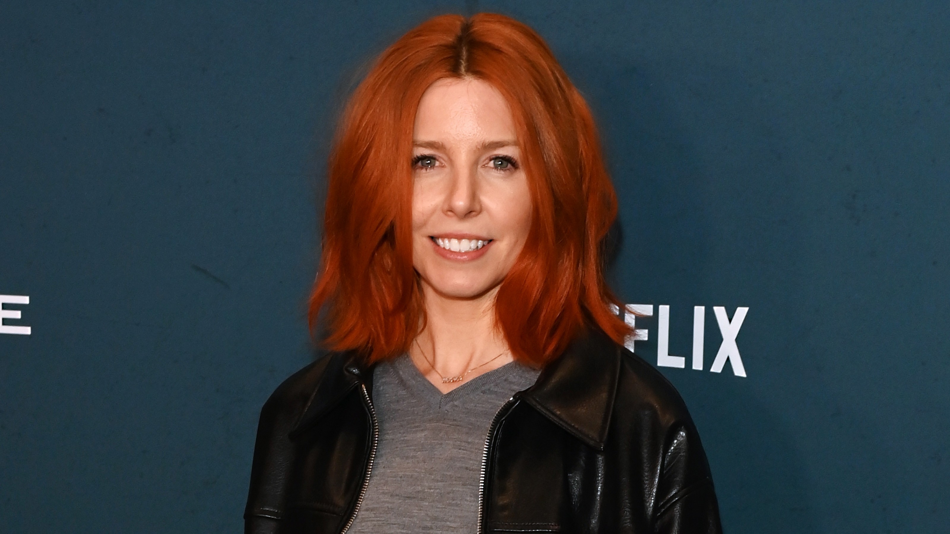 Stacey Dooley on the red carpet wearing a leather jacket and a grey V-neck sweater