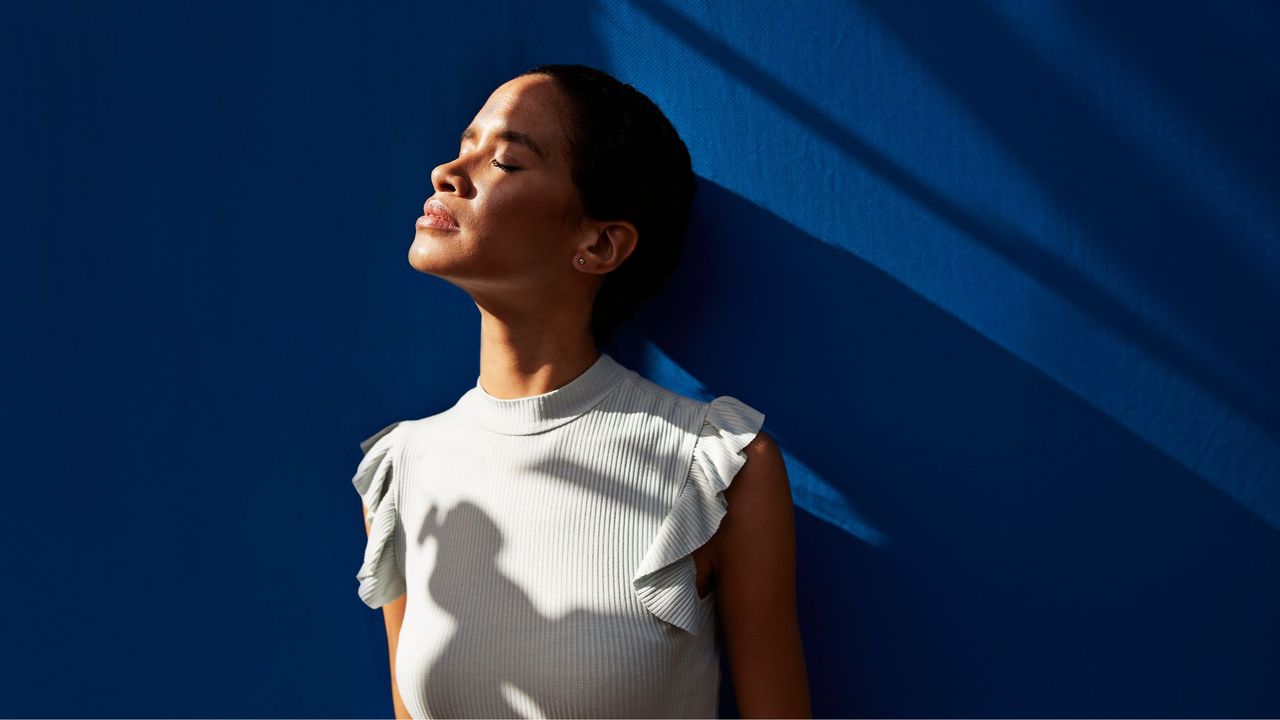 Trauma responses: A woman facing away against a blue wall