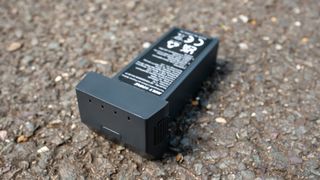 The black battery pack of the Holy Stone drone laid out on tarmac.