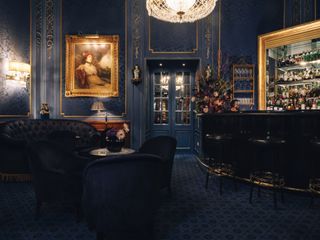 The dark blue interior of the Blaue Bar at the Sacher Hotel in Vienna includes brocade walls and lacquered furnishings