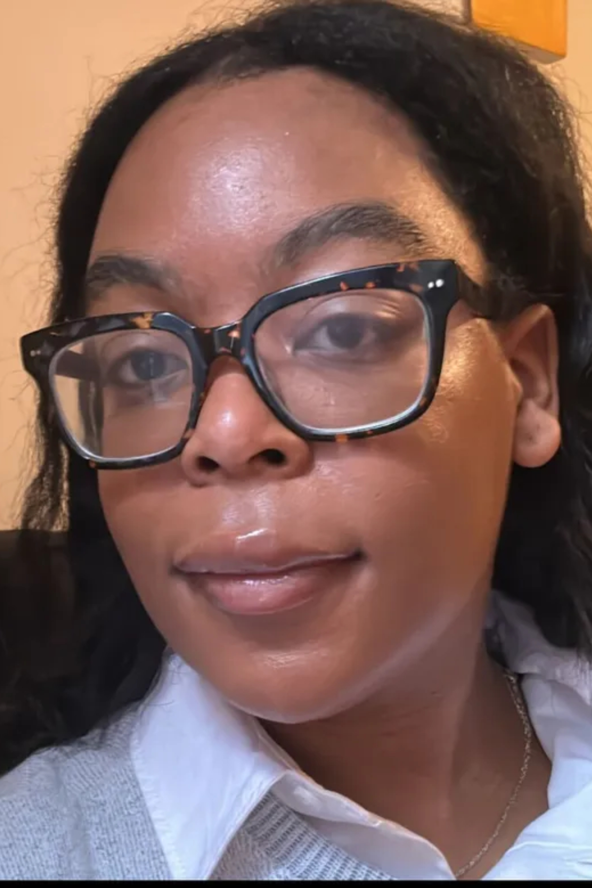 Ariel Baker after testing the Haus Labs Triclone Skin Tech Foundation wearing glasses and a grey sweater with a white collar.