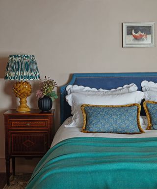 bedroom with blue headboard and bedding and lamp