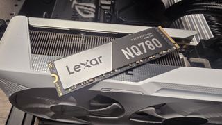 A Lexar NQ780 SSD installed inside a gaming PC and on top of a graphics card.