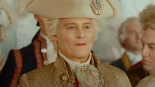 Johnny Depp smiles coyly dressed as Louis XV in Jeanne du Barry.