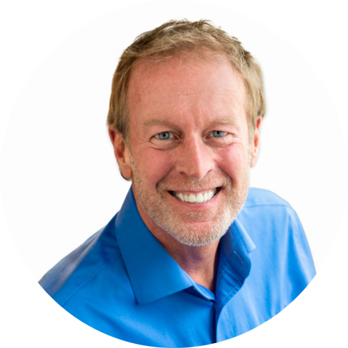 Robert is a white man wearing a blue collared shirt and smiling at the camera against a white background