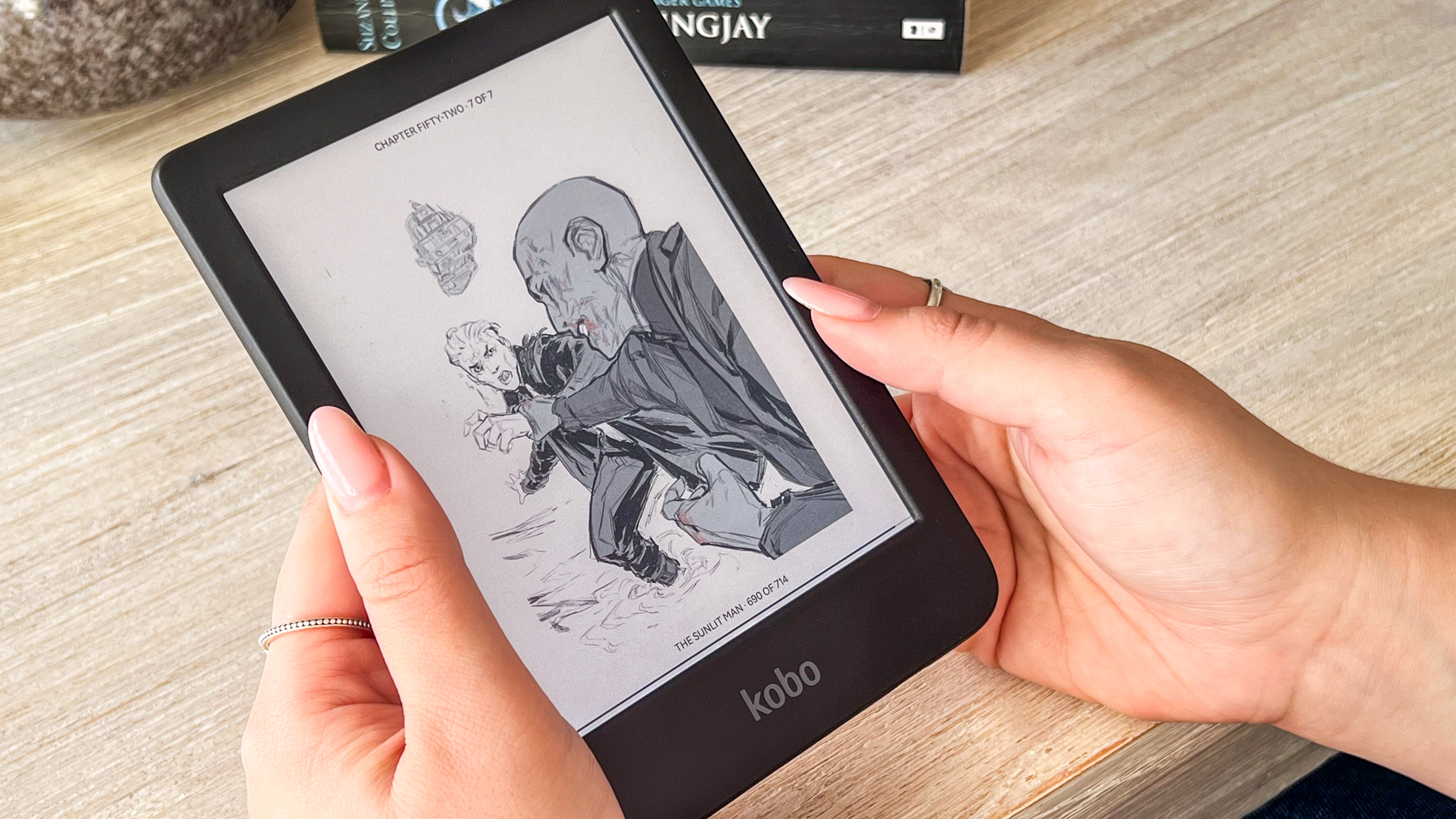 A person holding the Kobo Clara Colour ereader displaying an illustration